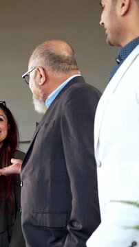 Indian Asian young business professional or businessman confidently shaking hands across a table with a colleague after finalizing a significant business deal or new project in modern corporate office