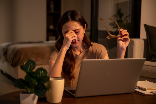 Exhausted woman suffering eye strain working late