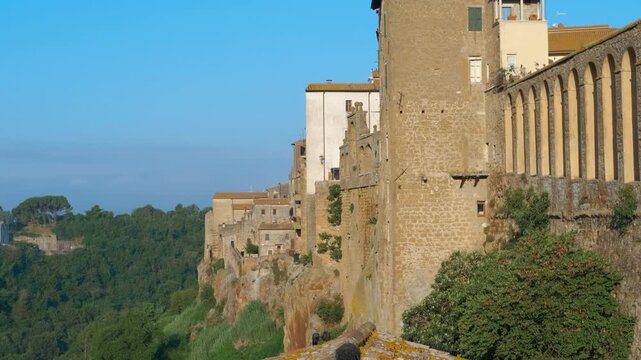 Medieval italian village pitigliano tilting downward. Picturesque medieval village of pitigliano slowly appearing from behind a tiled roof, showing the ancient stone buildings built on a tuff cliff