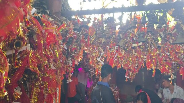 Visitors at a colorful temple adorned with bells and decorations