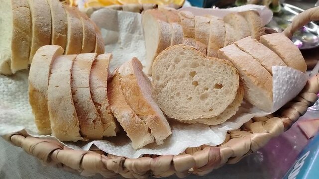 Sliced white bread arranged in a woven basket with paper napkin, showcasing the texture and freshness of the bread in a cozy kitchen setting
