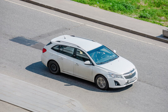 Chevrolet Cruze auto rides on a street. White 5-door station wagon motor car rushes on the road with blurred background
