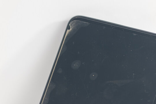 Close up of dirty smartphone screen with air bubbles under screen protector and dust particles on black display