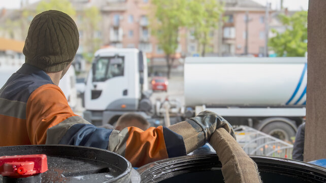 Worker monitoring water tank filling process at industrial site or city street.