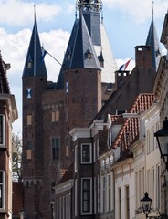 Obraz premium Ancient brick gatehouse tower rising above traditional residential homes in a historic dutch city center