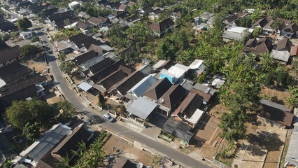 Fototapeta premium Aerial view of a peaceful rural village settlement surrounded by lush green tropical trees.