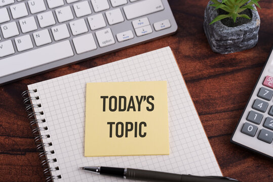 Office desk with notepad and adhesive note with text Today's topic