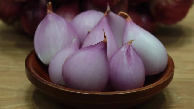 Peeled shallots in a wooden bowl.