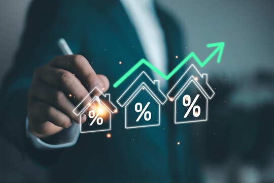 Businessman analyzing rising mortgage interest rates with glowing house icons and financial growth chart. Real estate investment, property market trends and home loan concept.