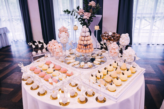 Elegant wedding dessert table with pastel macarons, meringues and cake pops at reception celebration