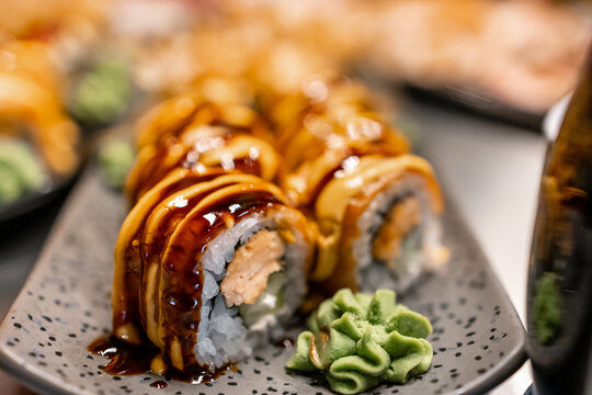 Gourmet sushi roll with sauce and wasabi served on a ceramic plate at a restaurant