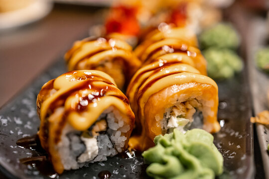 Delicious sushi rolls drizzled with spicy mayo and eel sauce served with fresh wasabi on a platter