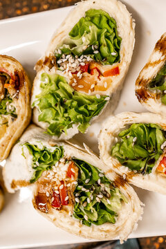 Fresh tortilla lettuce wraps with sesame seeds and roasted red pepper on a white plate