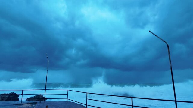 Standing on Flooded Pier &ndash; Enormous Wave Wall Approaching at Eye Level with Dramatic Storm Clouds and Light Break