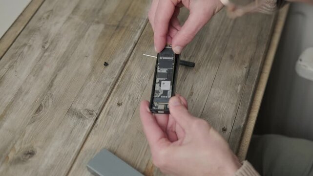 Compact NVMe M.2 SSD with USB adapter in male hands, high-speed external storage for laptops and PCs for professionals, SATA upgrade, portable storage solutions, Frankfurt - February 4, 2025