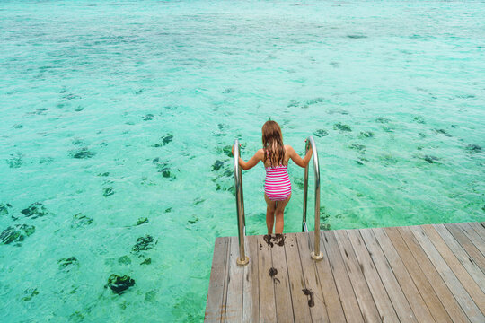 A girl on holiday, ready to dive in the crystal-clear water on a dream island, poster with copy space.