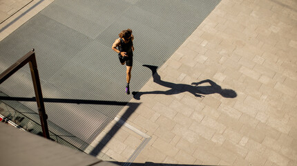 Naklejka premium Runner moves along the sidewalk in the urban area during daylight hours