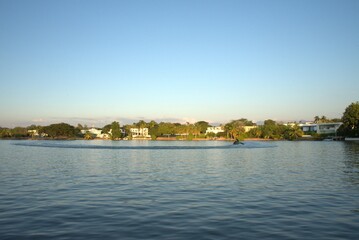 Obraz premium Scenic view of a luxury lakeside residential area with a person riding a jet ski on calm water