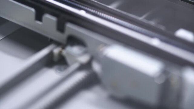 Close up of mechanical components inside flatbed scanner with metallic tones and soft lighting