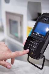 Customer entering pin on a payment terminal handheld device, completing a credit or debit card transaction in a retail store, showing modern banking and shopping process © Елена Попова