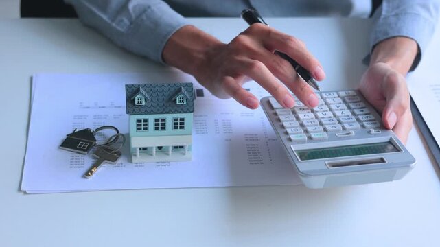 Real estate agent calculating and review documents for determine costs of housing, such as mortgage payment, down payment or closing fees associated with property purchase.