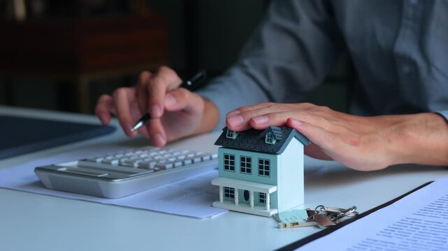 A person using calculator to determine costs of housing, such as mortgage payment, down payment or closing fees associated with property purchase.