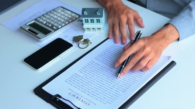 Close-up hand reading, signing contract for housing. Concept for real estate investment, home buying, selling, insurance, loan, lease, mortgage