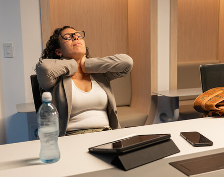 Woman stretching neck, relieving stress in office workspace
