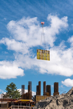 Canada, BC, Richmond.  A section of concrete form being lowered into place by  crane. 