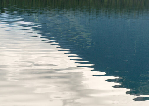 Canada, BC, Bowron Lake Provincial Park.  Graphic water ripples and hillside reflection, Isaac Lake