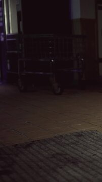 A floor is visible in a dim light. A vending machine is nearby, and several carts are positioned against the wall. The space feels busy and active without any people present.