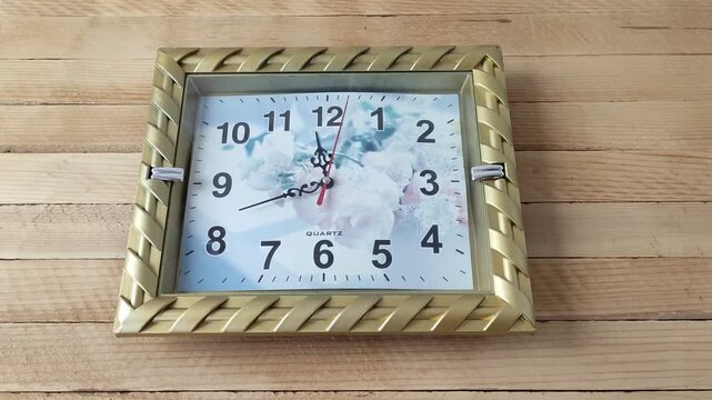 Square mechanical wall clock ticking on the wooden background