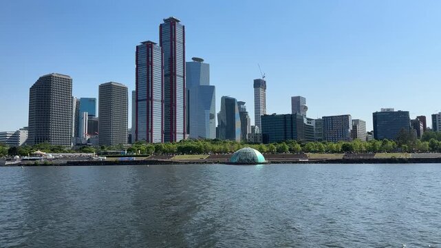 View of modern skyline on a clear day near a river with trees and buildings in the foreground and background in Mexico City