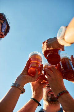 People holding beer cups and enjoying summertime outdoors.