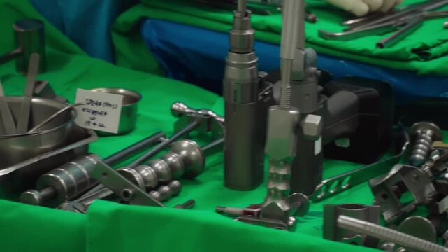 Surgical clamps and medical equipment on green surgical tray inside operating room. Sterile surgical instrument tool equipment for surgery.