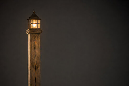 A fence post topped with tiny lit lanterns instead of regular caps