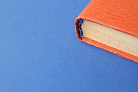 A book with a blue and orange cover on a colored paper background. Concept: Books as a source of information and knowledge that influence human development and education. Reading books develops creati