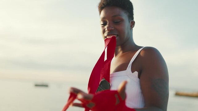 Black female fighter wrapping her hands for boxing training outdoors
