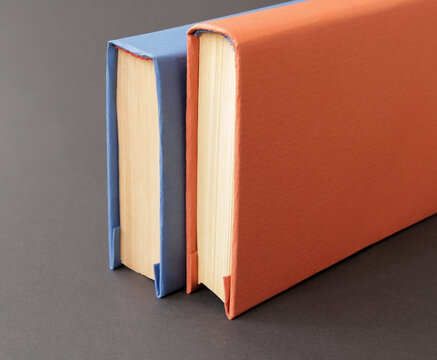 A book with a blue and orange cover on a colored paper background. Concept: Books as a source of information and knowledge that influence human development and education. Reading books develops creati