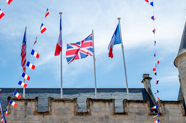  France, United Kingdom flags blowing in the wind above The oldest city hall building in operation. The 15th century fortified building features turrets and crenellations © Doodeez