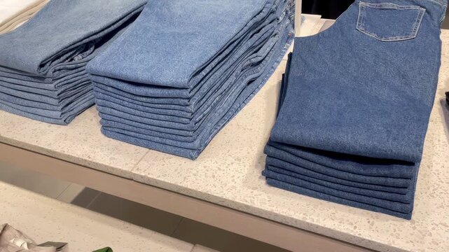 Neatly stacked denim jeans and folded clothes on a retail display table