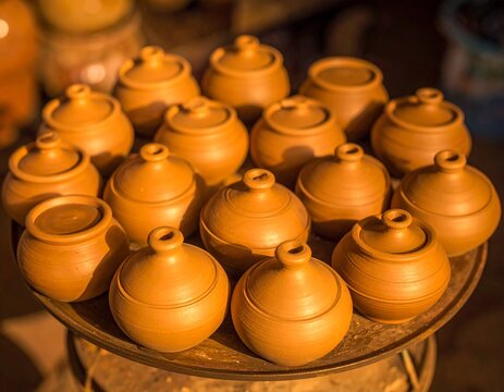 A close-up view of freshly made small clay pots arranged neatly on a circular tray, showcasing wet texture, smooth finishing, and traditional pottery craftsmanship in a workshop setting.