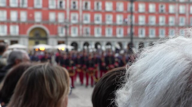 Crowd of spectators watching a military band parade performance at Plaza Mayor in central Madrid during a public cultural event