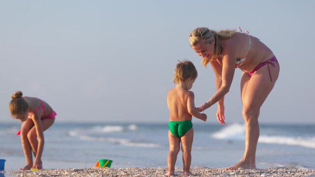 Mom plays with her children: daughter and baby, building beads and castles decorating them with shells