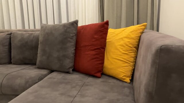Three colorful pillows on a gray sofa in a modern living room setting