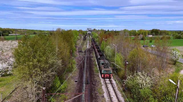 Aerial drone movi of EL2 Crocodile electric locomotive during brown coal loading mine, freight train with wagons at the loading terminal, mining infrastructure, industrial railway surrounde