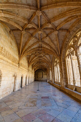 Naklejka premium Interior corridor of Jeronimos Monastery in Lisbon Portugal with vaulted ceiling, stone arches and historic Manueline architecture, famous UNESCO heritage site