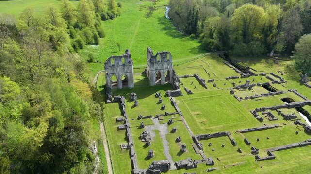 Aerial view of the historic stone ruins of Roche Abbey nestled among vibrant green trees and meadows in Maltby, England, United Kingdom.