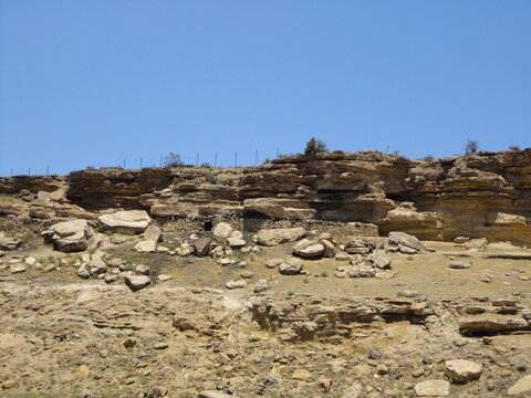 Scenic view of ancient rock shelters and stone walls built into the rugged cliffs of Tarom, Zanjan. This high-altitude shot highlights traditional mountain architecture in northern Iran.