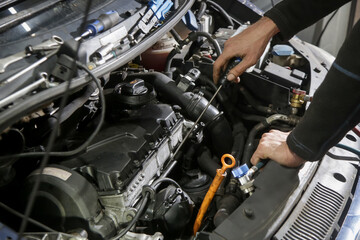 Fototapeta premium Car Maintenance - Mechanic Checking Engine Oil Level Using Dipstick at Workshop